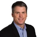 Headshot of Jeffrey Skibitsky, host of the Autism Weekly Podcast for ABS Kids, wearing a black blazer and blue shirt, smiling for the camera.