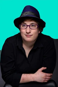 Robyn Steward, an advocate for autism awareness, poses for a portrait wearing a black shirt and a blue hat. She is featured on the Autism Weekly Podcast, where she discusses important topics related to the autism community. Robyn brings her insights and personal experiences to the conversation, contributing to ABS Kids' ongoing efforts to create meaningful dialogue and support for individuals with autism. The vibrant teal background adds a touch of energy to this empowering image.